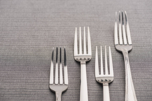 Close up view of shiny forks on grey tablecloth  - 写真・画像