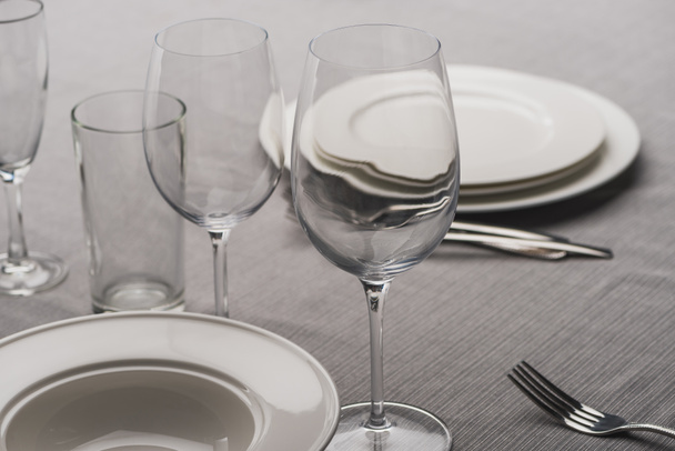 Serving dishware with glasses on grey tablecloth - Photo, Image