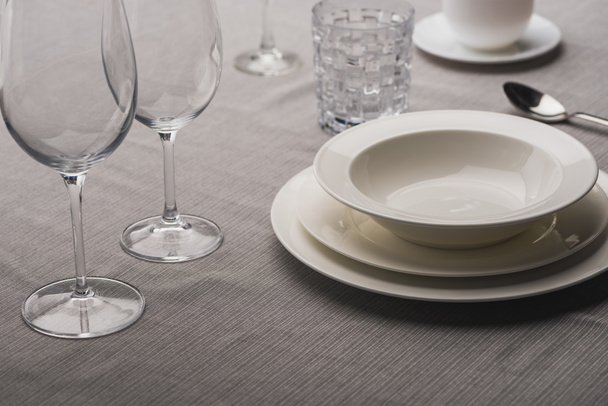 Serving tableware with wine glasses on grey tablecloth - Fotografie, Obrázek