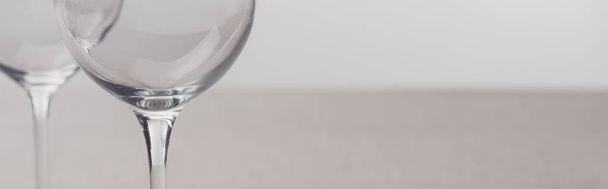 Panoramic shot of clear wine glasses isolated on grey - Фото, изображение