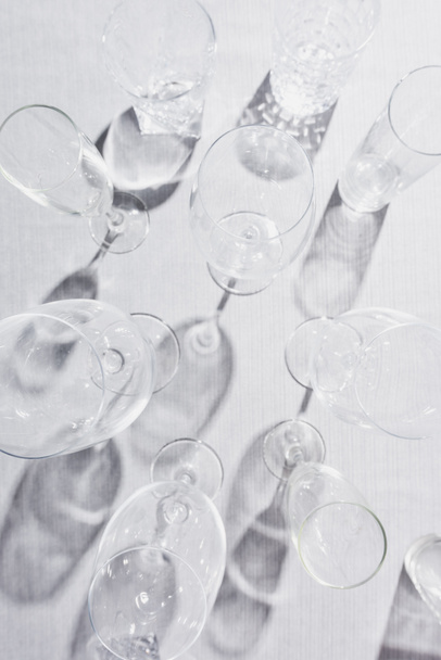 Bovenaanzicht van transparante glazen met schaduw op grijze doek - Foto, afbeelding
