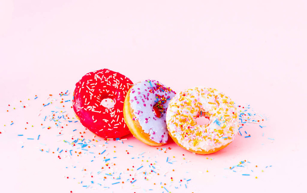 Renkli çörekler ve pembe arka planda rengarenk şekerler. Boşluğu kopyala - Fotoğraf, Görsel