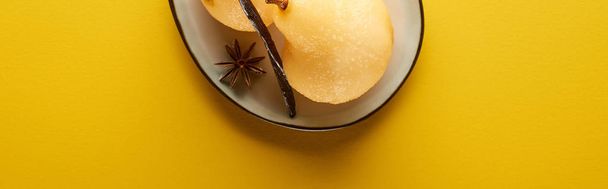 top view of delicious pear in wine with anise on plate on yellow background, panoramic shot - Φωτογραφία, εικόνα