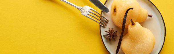 top view of delicious pear in wine with anise on plate near cutlery on yellow background, panoramic shot - Foto, afbeelding