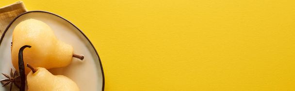 vista superior de pêra deliciosa no vinho com anis na placa no guardanapo no fundo amarelo, tiro panorâmico
 - Foto, Imagem