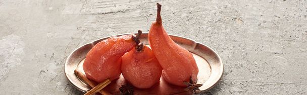 delicious pear in wine with cinnamon and anise on silver plate on grey concrete surface, panoramic shot - Valokuva, kuva