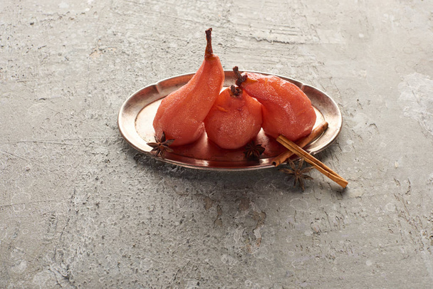 delicious pear in wine with cinnamon and anise on silver plate on grey concrete surface - Foto, Imagen