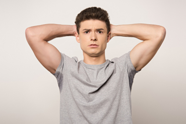 shocked man in grey t-shirt with sweaty underarms looking at camera isolated on grey - Foto, afbeelding