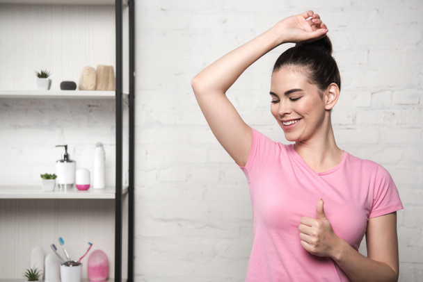 smiling woman showing thumb up while looking at underarm - Photo, Image