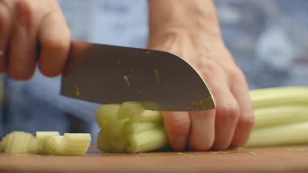 Close-up van gesneden selderij op een plank in de keuken met een mes - Video