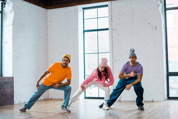 stylish multicultural men and girl in hats breakdancing - Photo, Image