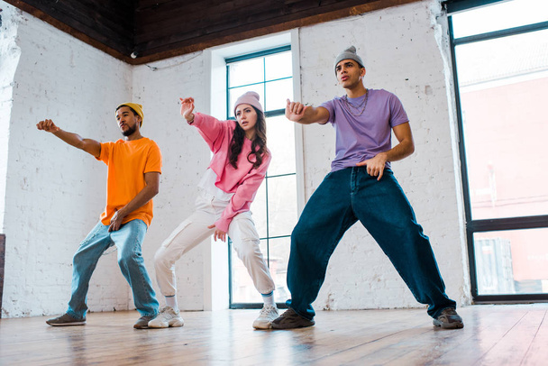 handsome multicultural men gesturing while breakdancing with attractive girl  - Valokuva, kuva