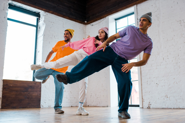 stylowe wielokulturowe mężczyźni w kapelusze breakdance z piękną kobietą  - Zdjęcie, obraz