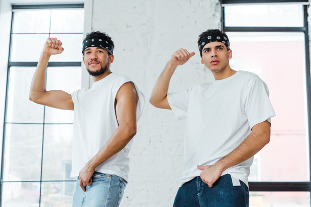 handsome multicultural dancers in headbands posing while dancing hip-hop - Foto, imagen