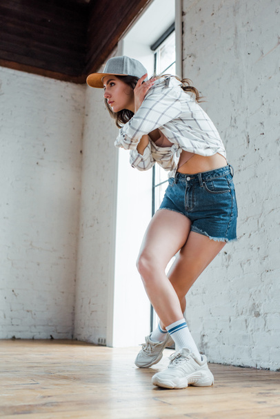 attractive dancer in cap posing while dancing hip-hop  - Photo, image