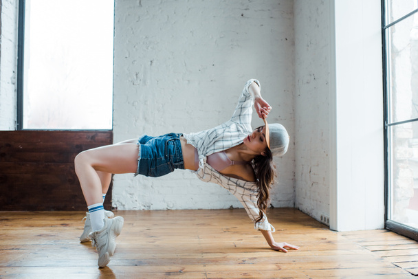 привлекательная девушка трогает кепку, танцуя хип-хоп в танцевальной студии
  - Фото, изображение