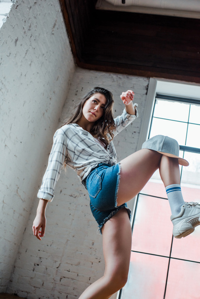 vista de ángulo bajo de bonita bailarina con gorra bailando hip-hop en estudio de baile
  - Foto, imagen