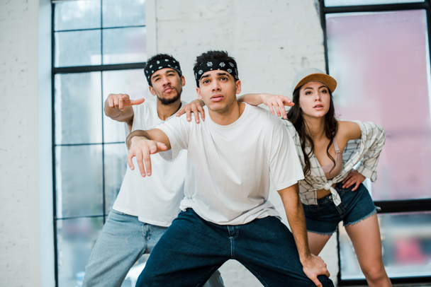 stylish multicultural dancers posing while dancing hip-hop in dance studio  - 写真・画像
