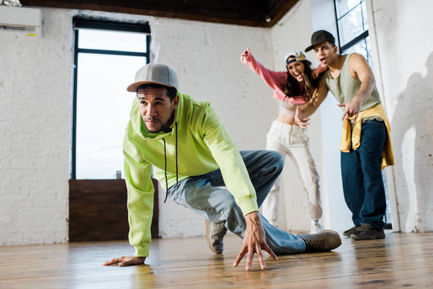 selective focus of handsome african american dancer breakdancing near emotional man and woman - Foto, Bild