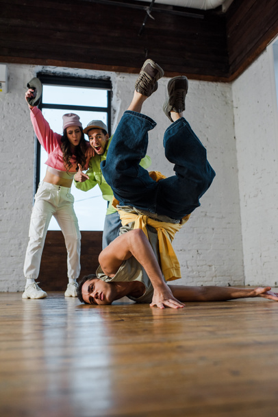 selective focus of handsome man breakdancing near excited multicultural dancers  - Photo, Image