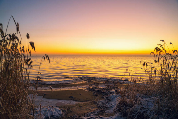 Pierwsze promienie słońca nad jeziorem Ladoga rano w zimie. - Zdjęcie, obraz