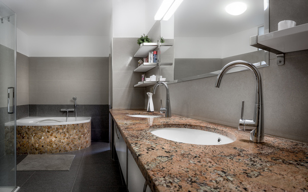 Salle de bain moderne dans un style cool avec douche en verre et baignoire bordée de pierres rouges et marbre
. - Photo, image