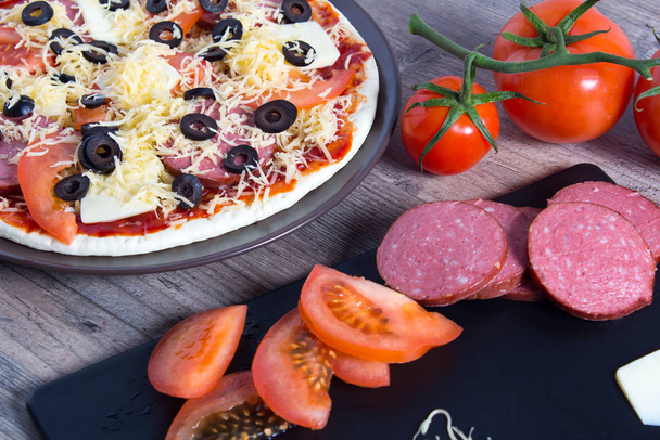 Cocinar pizza en casa. Pizza con tomates, aceitunas y queso es
 - Foto, imagen