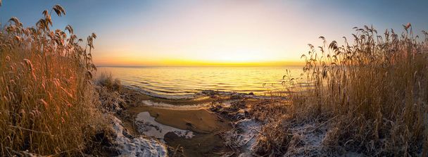 Pierwsze promienie słońca nad jeziorem Ladoga rano w zimie. Obwód leningradzki . - Zdjęcie, obraz