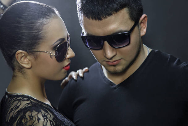 Attraente giovane coppia indossa occhiali da sole su sfondo nero
 - Foto, immagini