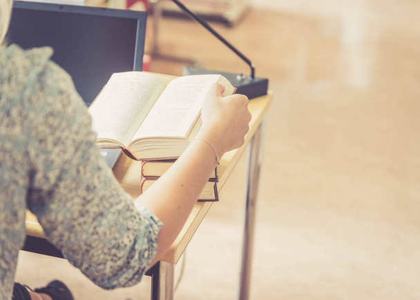 Blondynka studentka siedzi przy biurku z kupą książek, biblioteka uniwersytecka - Zdjęcie, obraz