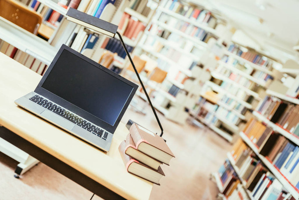 Laptopot és egy halom könyvet egy fa asztalon. Egyetemi könyvtár. - Fotó, kép