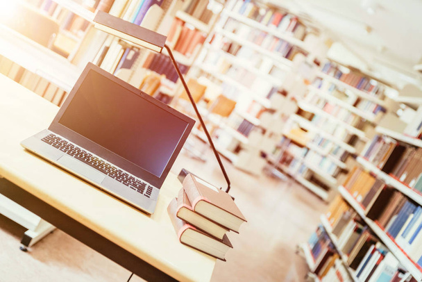 Laptopot és egy halom könyvet egy fa asztalon. Egyetemi könyvtár. - Fotó, kép