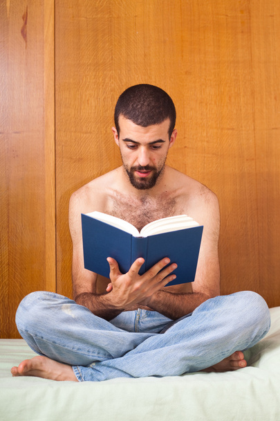 Man reading a book on the bed - Φωτογραφία, εικόνα