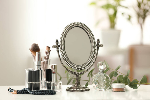 Mirror and makeup products on white table indoors - Photo, image