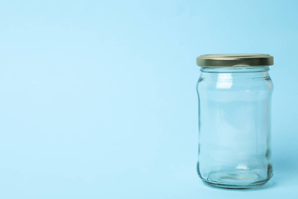 Closed empty glass jar on light blue background, space for text - Zdjęcie, obraz