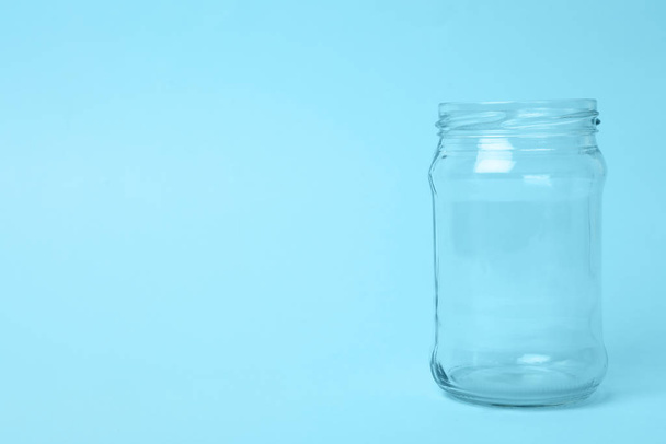 Open empty glass jar on light blue background, space for text - Fotografie, Obrázek