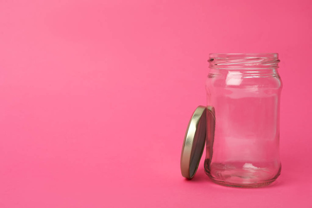 Open empty glass jar on pink background, space for text - Фото, изображение
