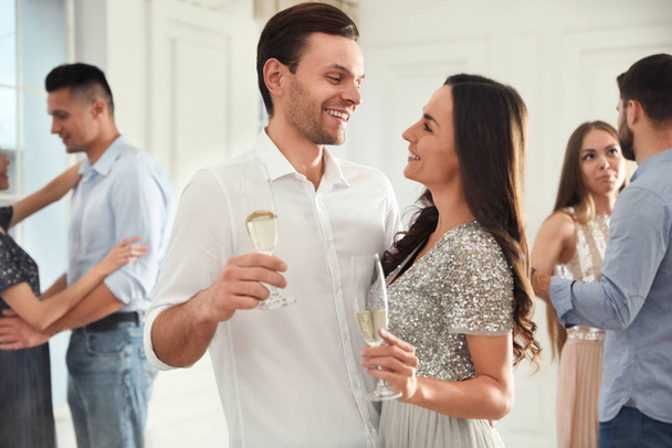Lovely young couple with glasses of champagne at dancing party - 写真・画像