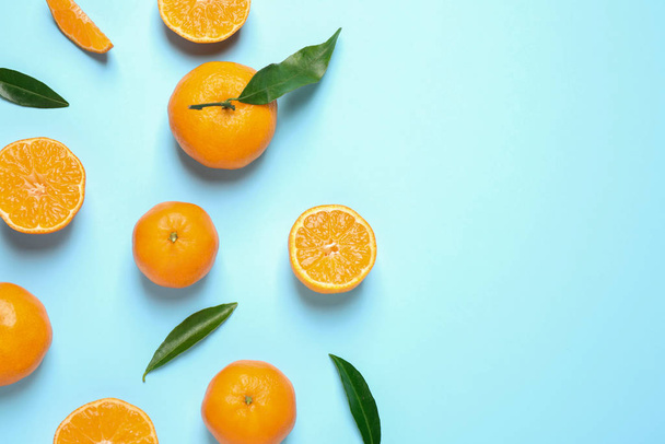 Flat lay composition with fresh ripe tangerines and leaves on light blue background, space for text. Citrus fruit - Фото, зображення