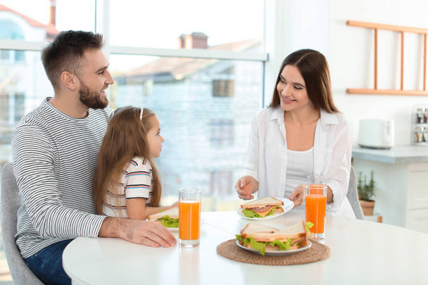 Happy family having breakfast with sandwiches at table in kitche - Valokuva, kuva