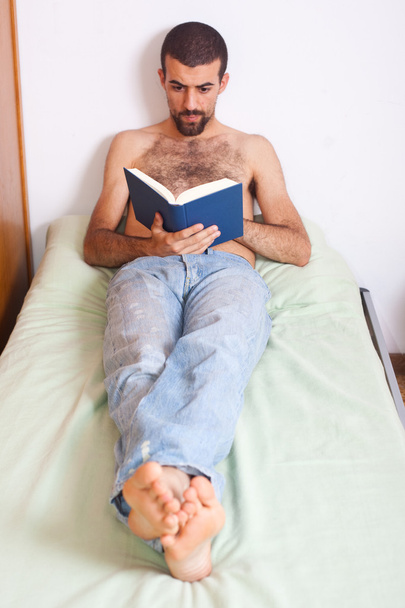 Man reading a book on the bed - Fotoğraf, Görsel