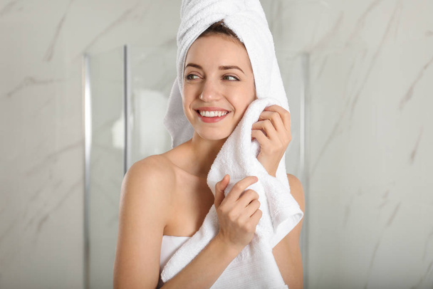 Young woman wiping face with towel in bathroom - Фото, зображення