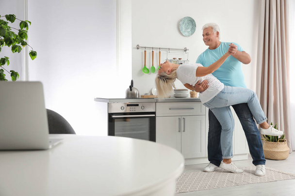 Happy mature couple dancing together in kitchen - Photo, Image