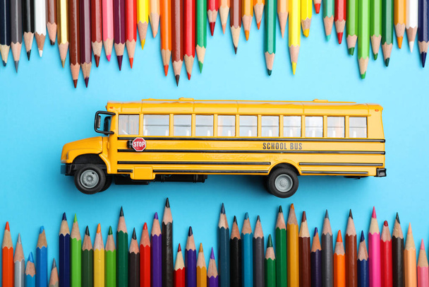 Flat lay composition with yellow school bus model on light blue  - Foto, Imagen