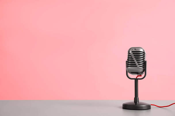 Vintage microphone on table against pink background, space for text - Photo, Image