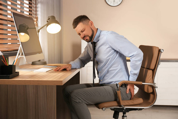 Man suffering from hemorrhoid at workplace in office - Zdjęcie, obraz