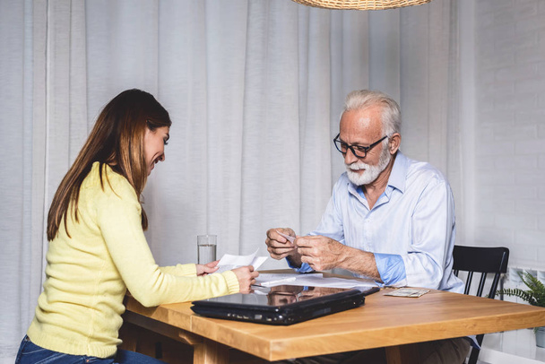 Tochter schenkt ihrem pensionierten Vater einen Gutschein. Gesichtsausdruck eines älteren Mannes im Ruhestand - Foto, Bild