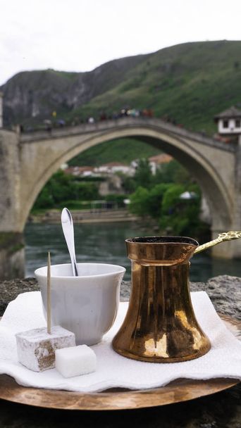 Боснийский кофе с восхитительным традиционным медным сервизом перед Старым мостом в Мостаре, Босния и Герцеговина
.  - Фото, изображение