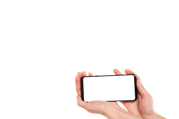 Beyaz arkaplanda modern çerçevesiz tasarımı olan siyah akıllı telefonu tutan kadın elleri - Fotoğraf, Görsel