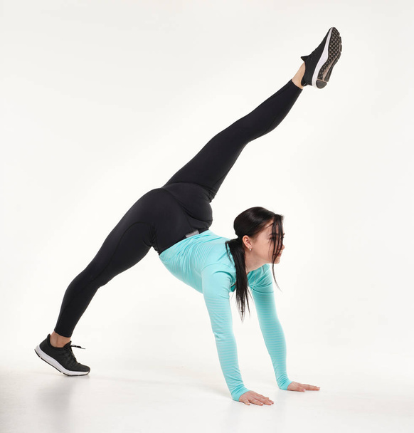 Young athletic woman making yoga and gymnastics stretching exercises isolated on white  - Photo, Image